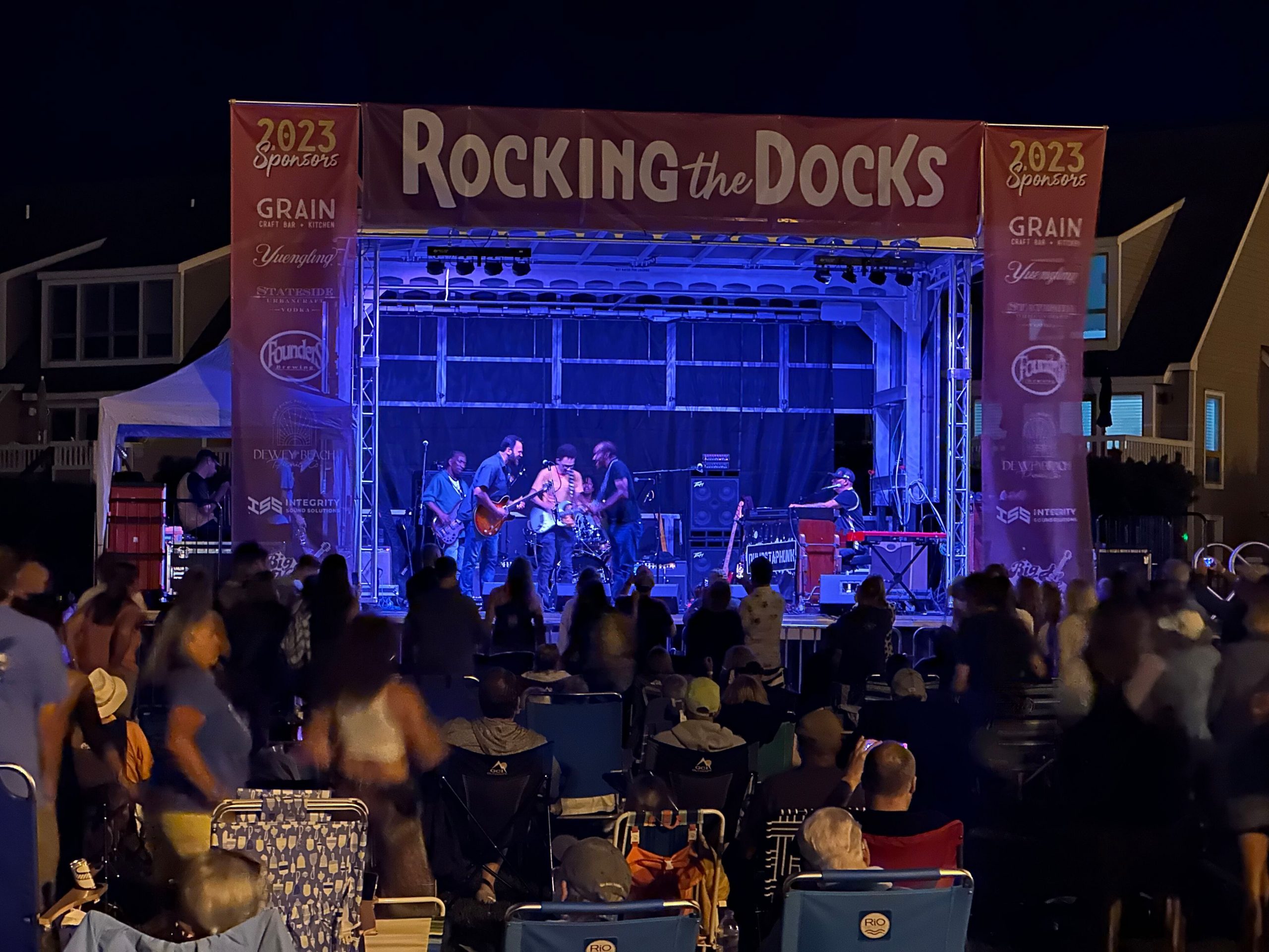 Image of a band performing on the Integrity Sound Solutions portable stage at night with lighting.